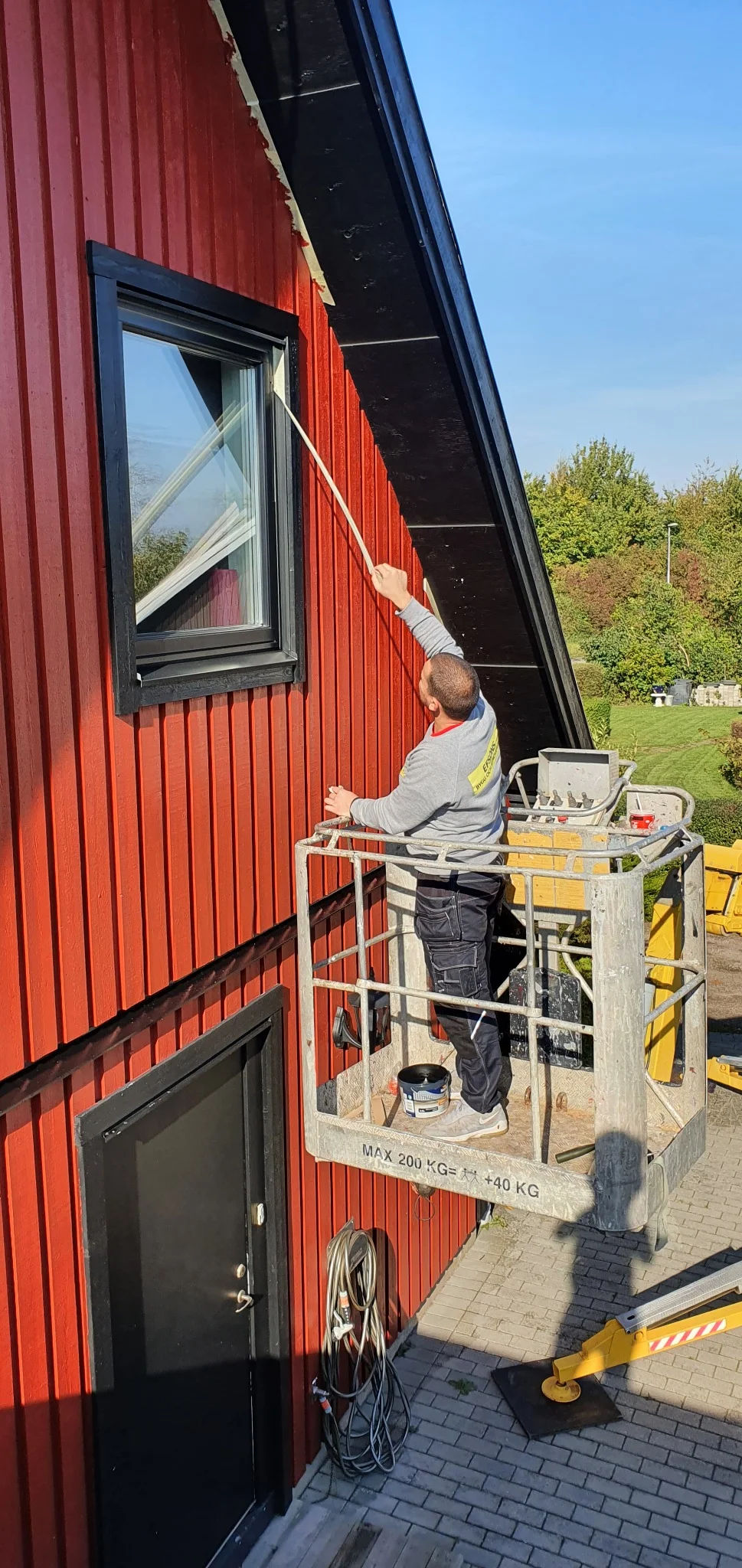 Målning av träfasad runt fönster på hus i Sunnanå, Burlöv